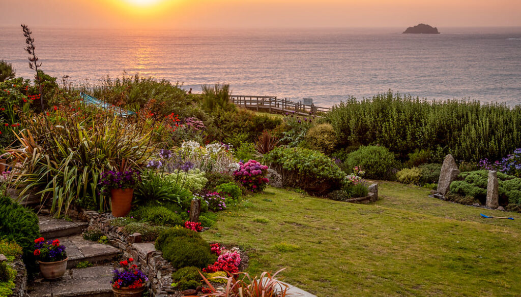Garden With Flowers And The Ocean And Sunset In The Distance