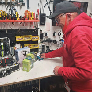 Cornwall Air Ambulance volunteer PAT testing electrical equipment in a charity shop