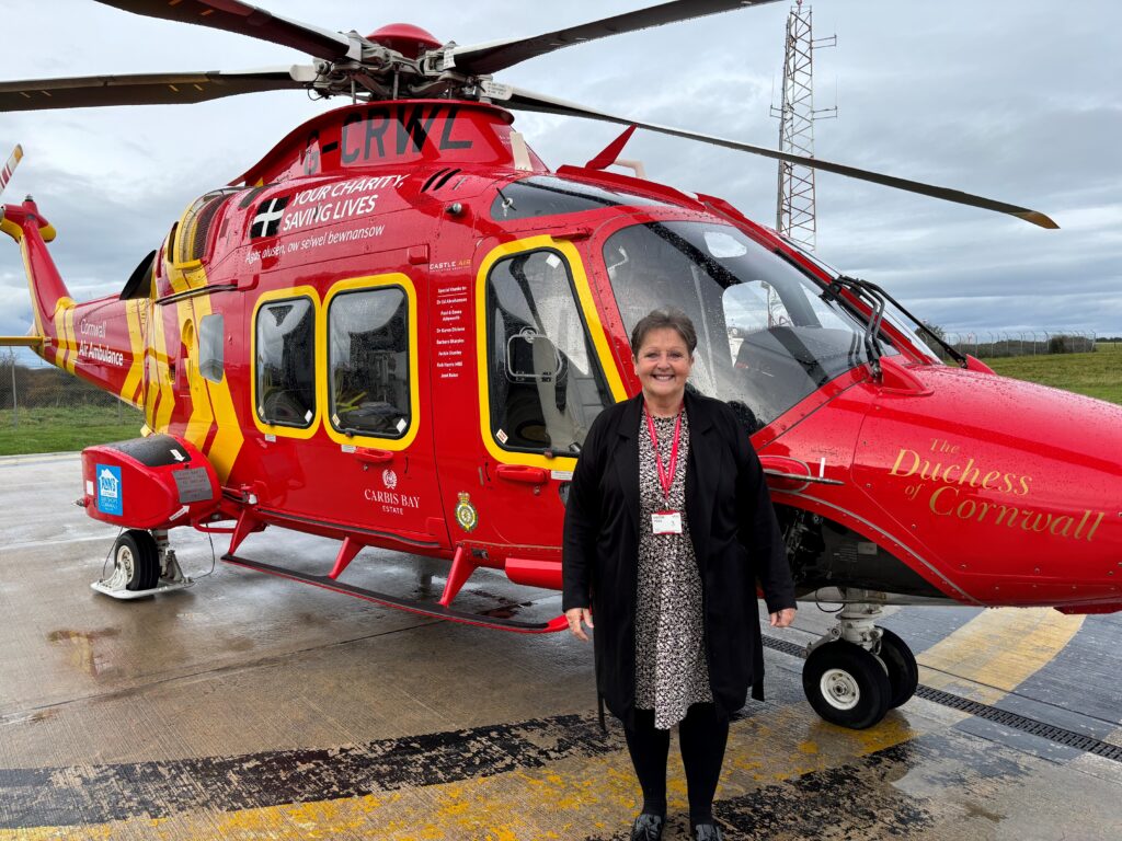 Jan Woolley in front of helicopter