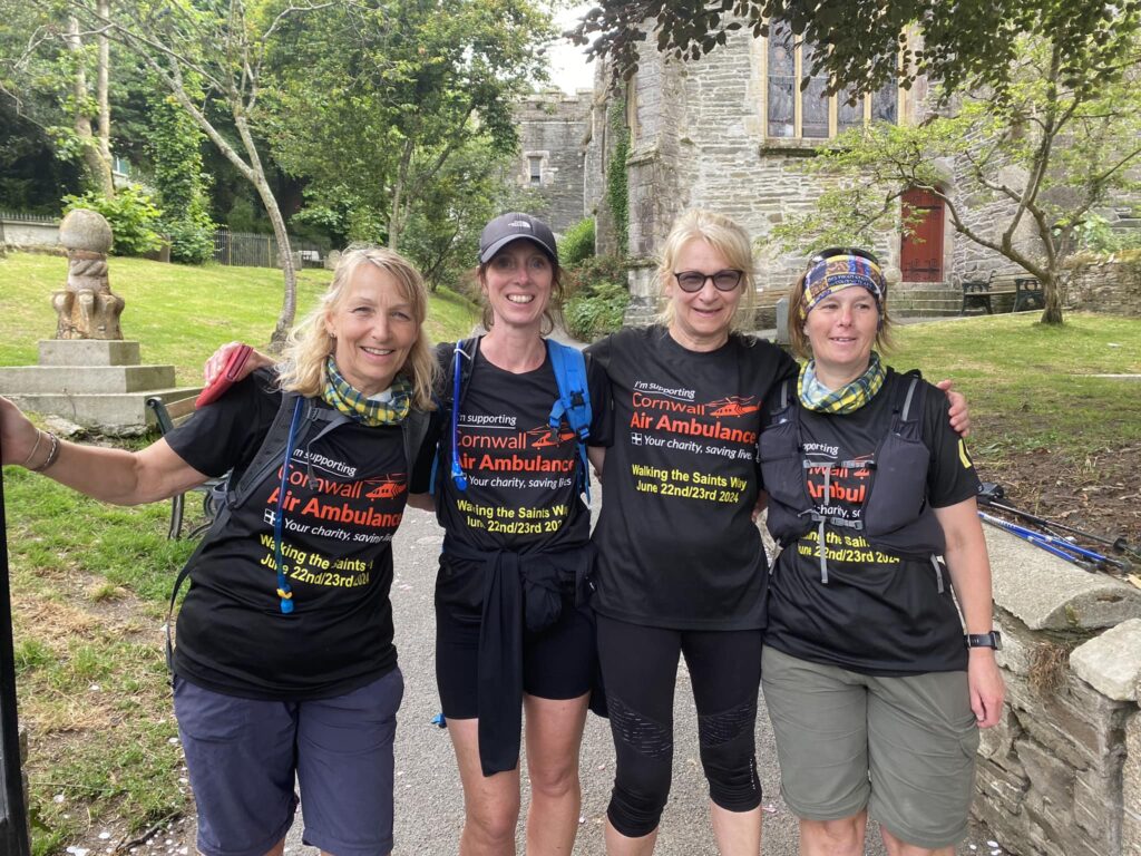 Lynnette and her three female friends hugging each other side by side in their walking gear on the Saints Way.